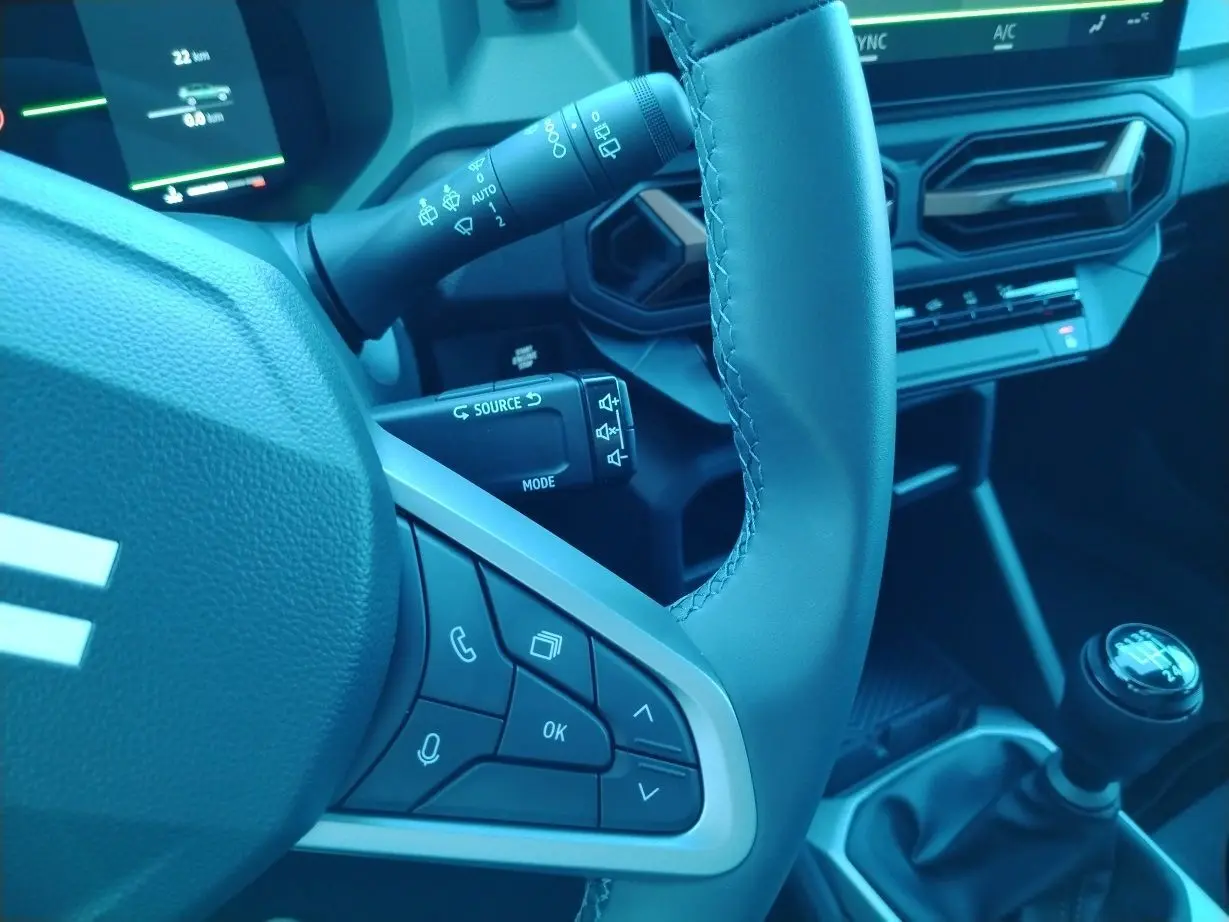 Gros plan sur le volant noir et la commande de boîte manuelle du Dacia Bigster 2025, avec tableau de bord digital en arrière-plan.