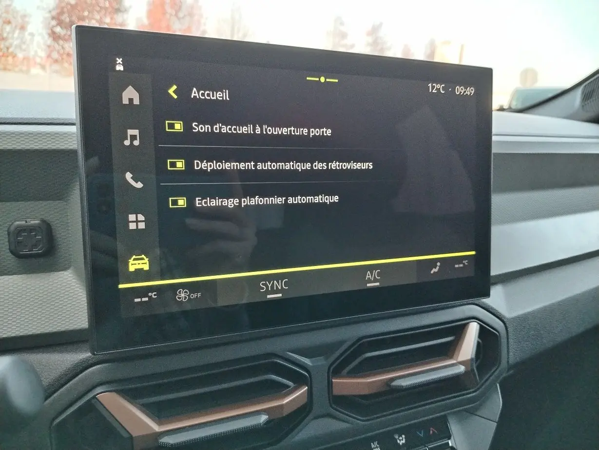 Écran tactile central du tableau de bord du Dacia Bigster 2025 noir, affichant les réglages d'accueil et d'éclairage.