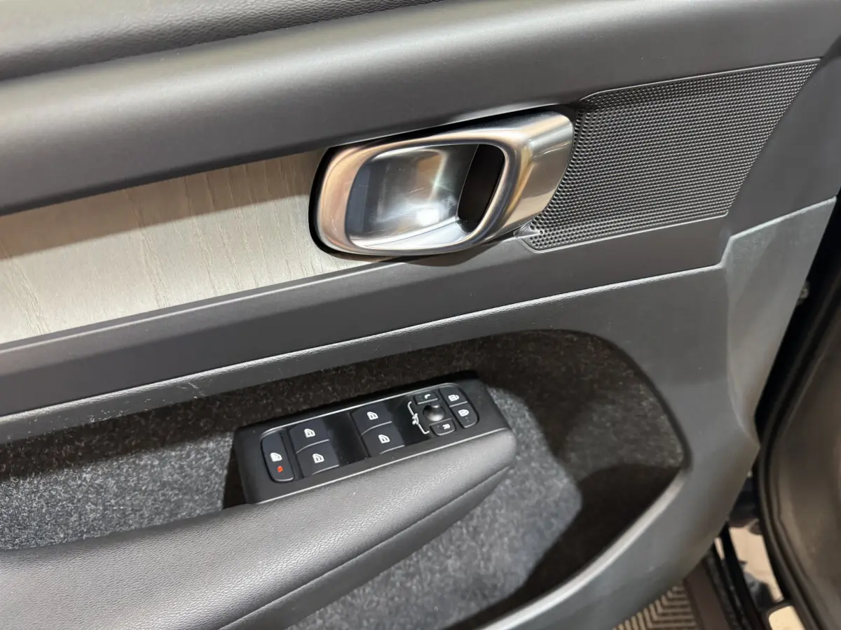 Gros plan sur la poignée intérieure et les commandes de vitres côté conducteur du Volvo XC40 noir, finition Inscription.