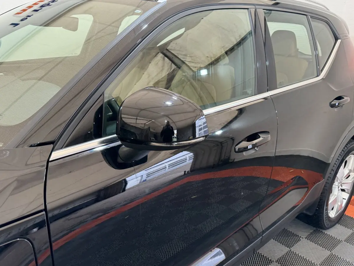 Vue latérale gauche du Volvo XC40 noir Recharge T5 avec rétroviseur et poignées de porte chromées.