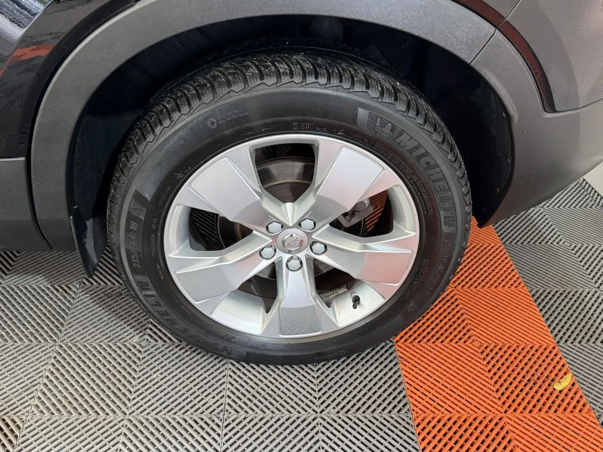 Gros plan sur la roue avant gauche avec jante argentée du Volvo XC40 noir Recharge T5 262 DCT7 Inscription 2021.