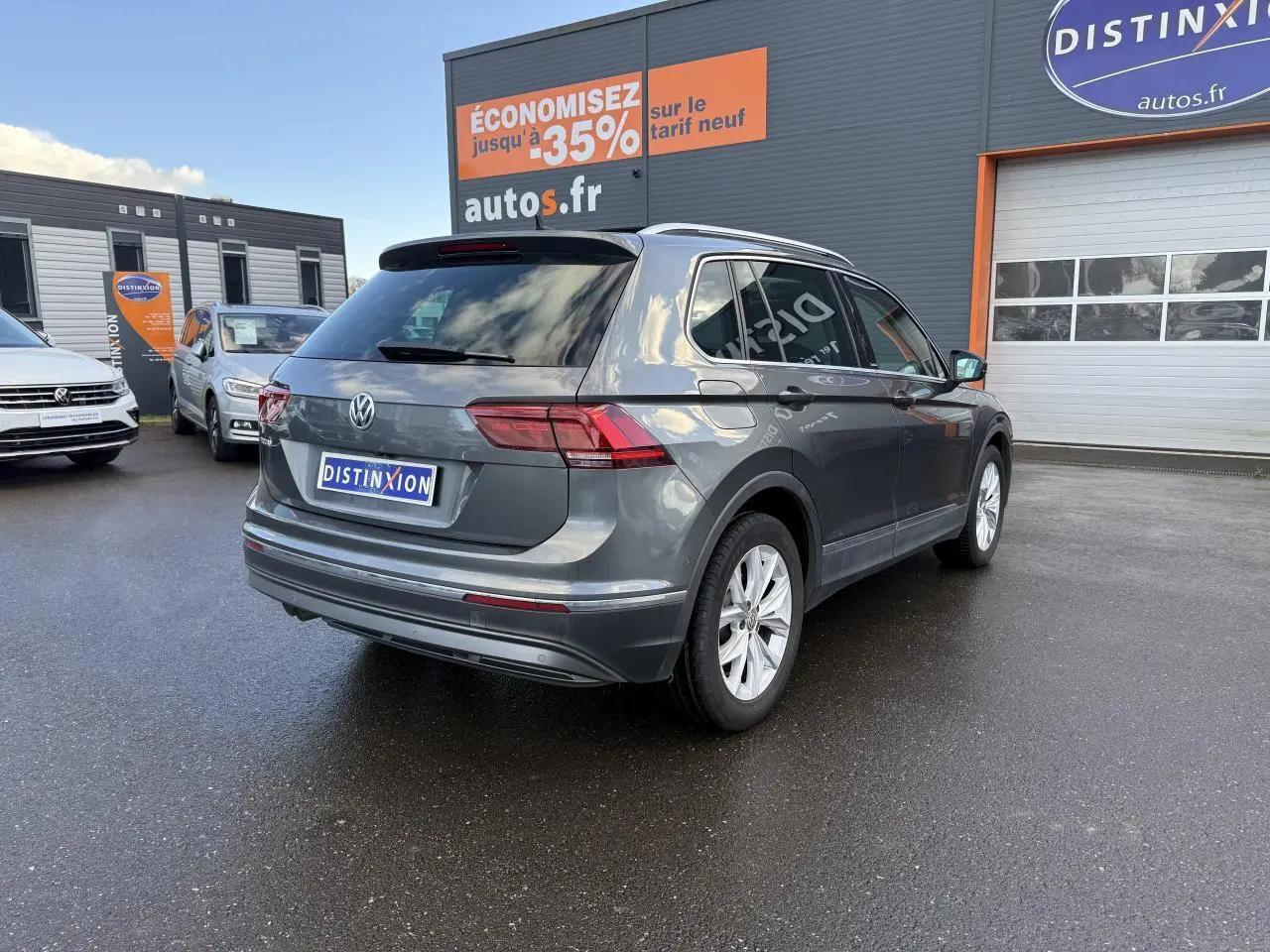 Volkswagen Tiguan gris Indium métallisé vu en 3/4 arrière droit sur parking devant un garage autos.fr