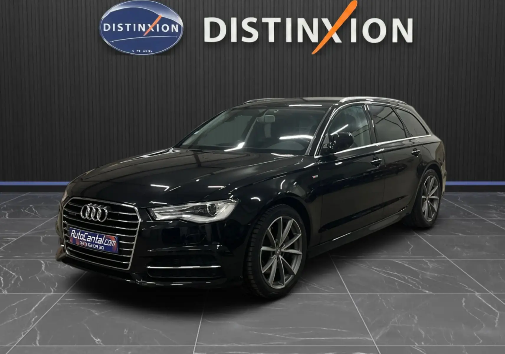 Audi A6 Avant noire vue en 3/4 avant droit dans un showroom avec jantes alliage et calandre chromée.