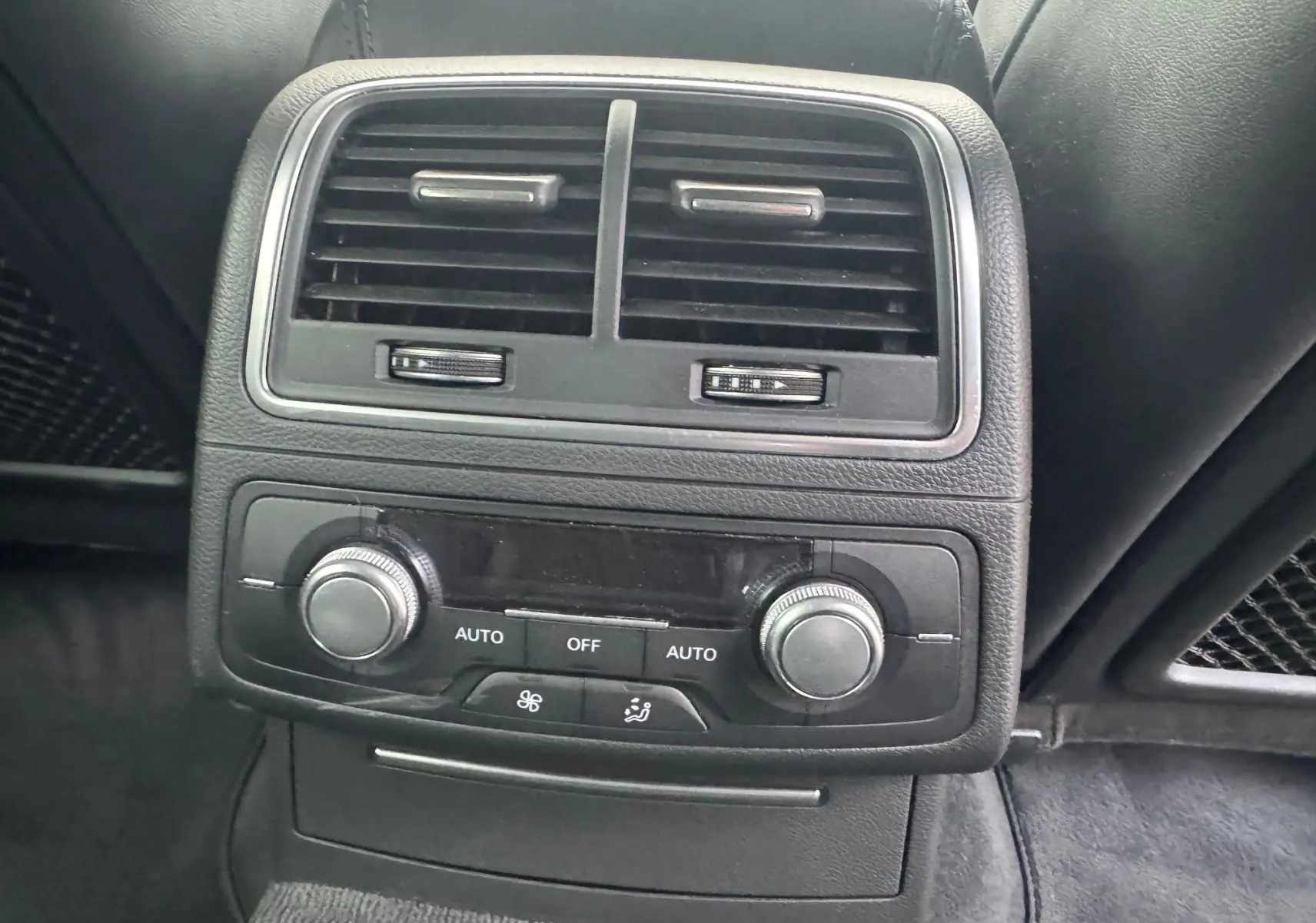 Vue rapprochée de la console de climatisation arrière noire de l’Audi A6 Avant 2015 avec commandes rotatives et aérateurs.