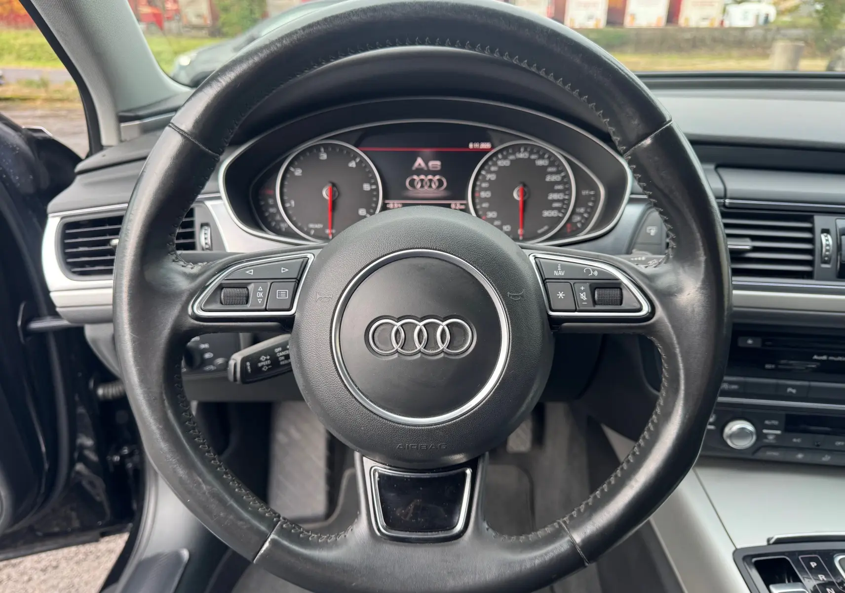 Vue centrée sur le volant en cuir noir de l'Audi A6 Avant 2015, avec tableau de bord et commandes visibles.