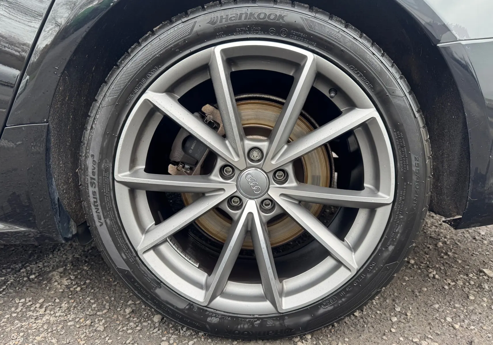 Gros plan sur la roue arrière droite d'une Audi A6 Avant noire de 2015 avec jante alliage 19 pouces et pneu Hankook.