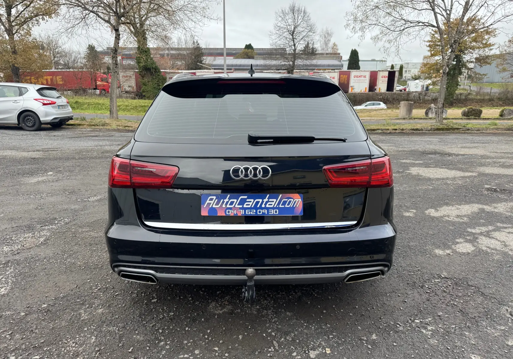 Vue arrière d'une Audi A6 Avant noire de 2015 avec feux LED et attelage de remorque visible sur un parking.