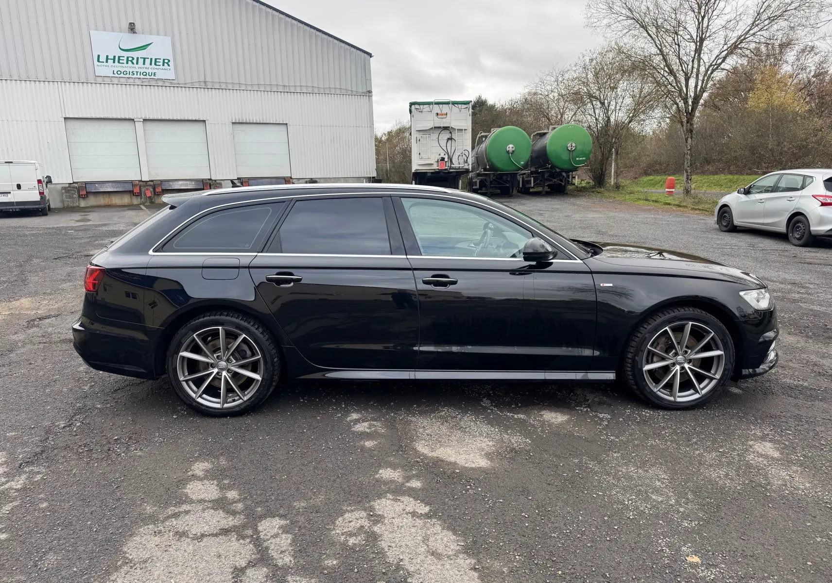 Audi A6 Avant noir vue de profil côté gauche, avec jantes alliage 19 pouces et vitres teintées.