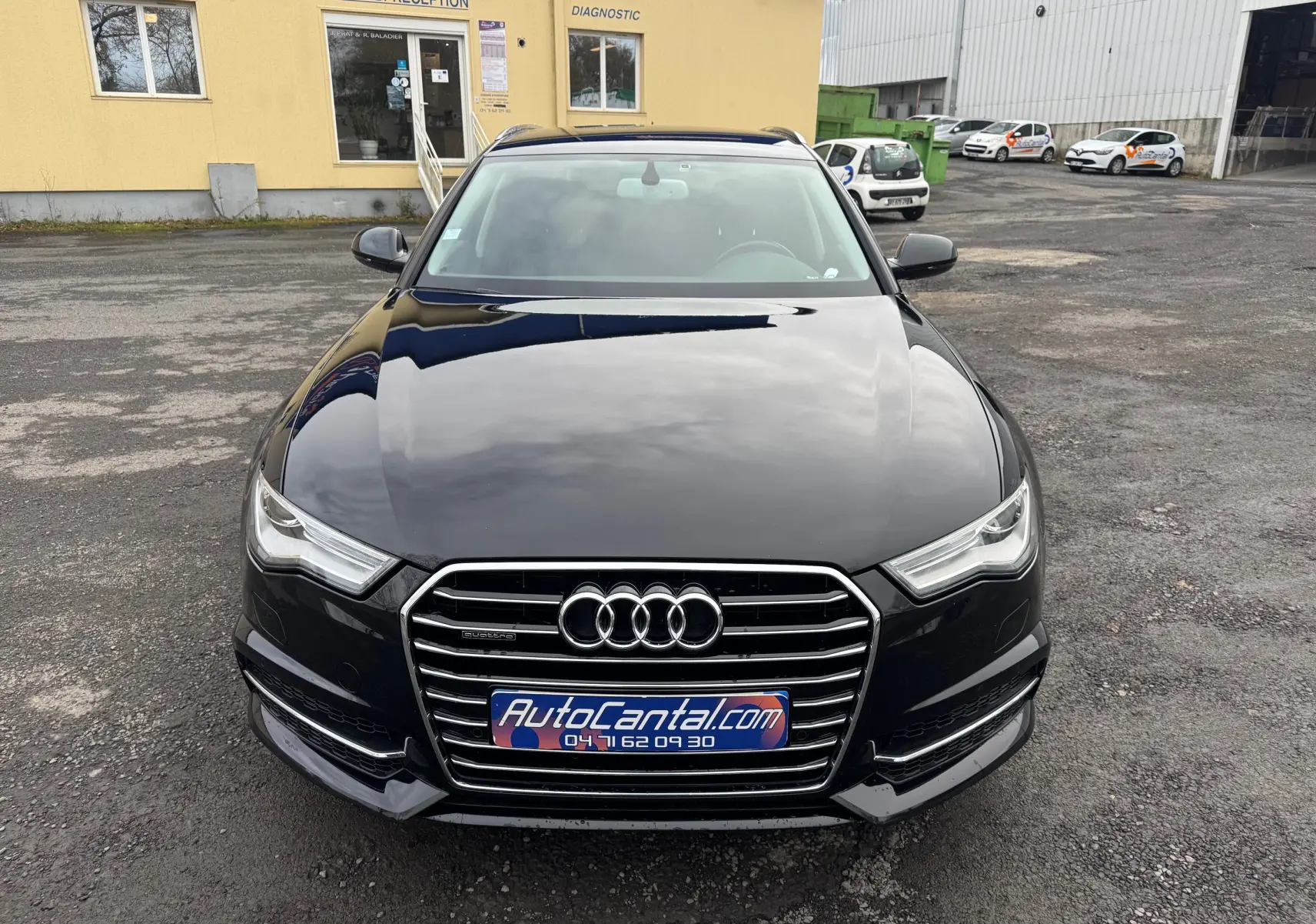 Vue avant d'une Audi A6 Avant noire de 2015, mettant en valeur sa calandre chromée et ses phares LED distinctifs.