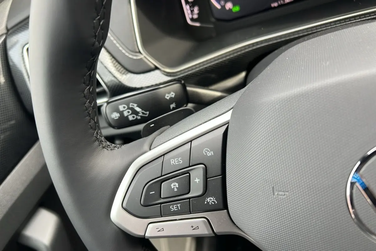 Gros plan sur le volant cuir multifonctions du Volkswagen T-Cross gris argent, avec commandes de régulateur de vitesse.