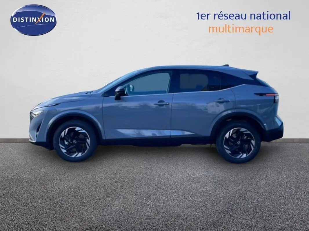 Vue de profil côté gauche du Nissan Qashqai gris 2025 avec jantes aluminium et barres de toit visibles.