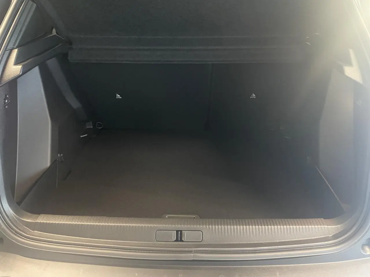 Coffre ouvert vu de face du Peugeot 2008 gris, montrant un espace de chargement vide et propre.