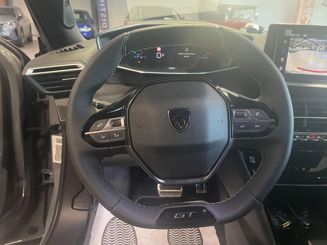 Vue intérieure centrée sur le volant cuir noir GT de la Peugeot 2008 1.2i Hybrid avec tableau de bord numérique.