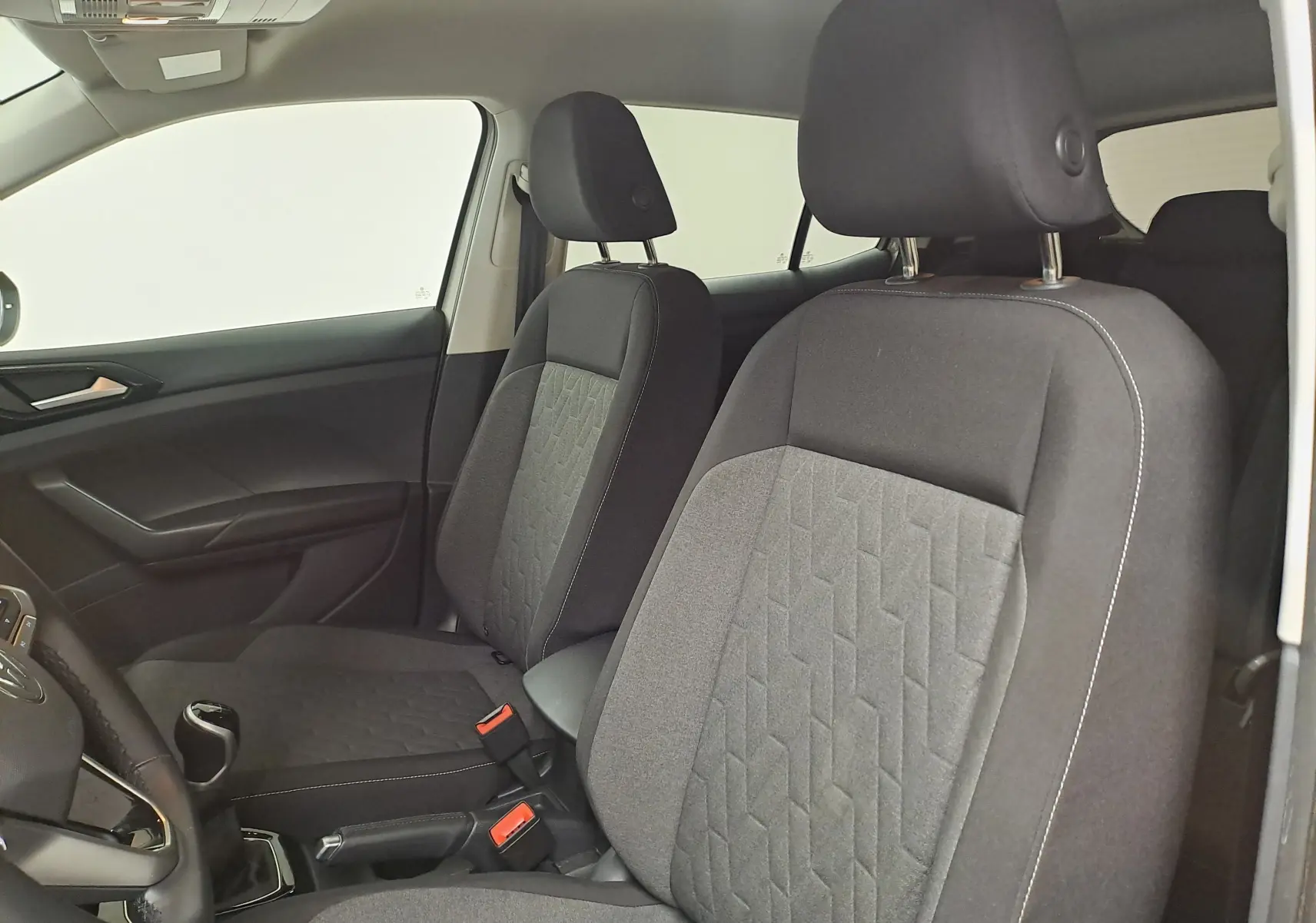 Vue intérieure du Volkswagen T-Cross 2024 montrant les sièges avant en tissu gris avec motifs géométriques.