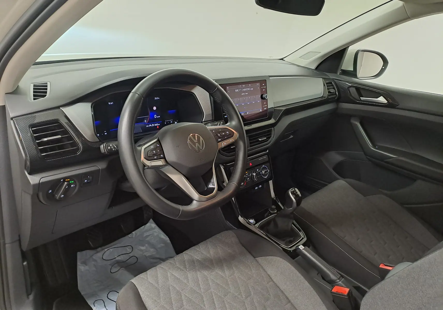 Vue intérieure côté conducteur du Volkswagen T-Cross 2024, tableau de bord moderne avec volant multifonction et boîte manuelle.