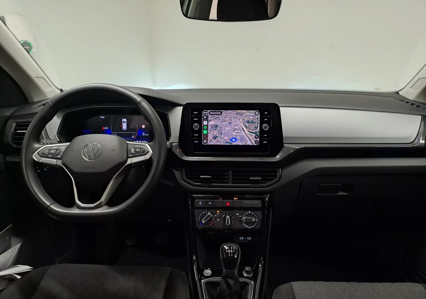 Vue intérieure frontale du tableau de bord du Volkswagen T-Cross 2024 avec écran tactile et volant multifonction noir.