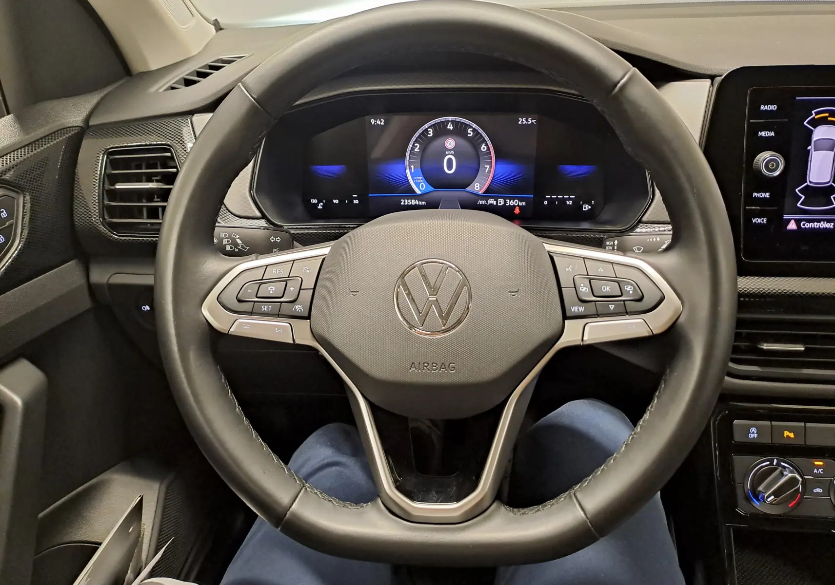 Vue intérieure centrée sur le volant cuir noir du Volkswagen T-Cross 2024 avec tableau de bord digital et commandes intégrées.