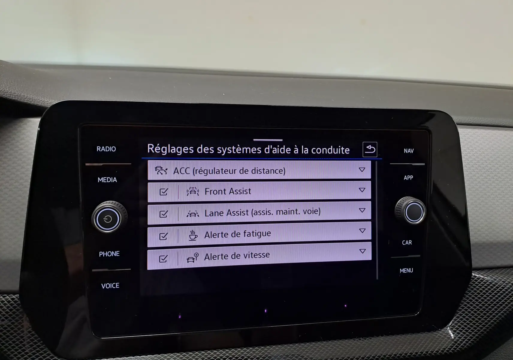 Écran tactile du système d’aide à la conduite du Volkswagen T-Cross 2024 affichant les réglages d’assistances activées.