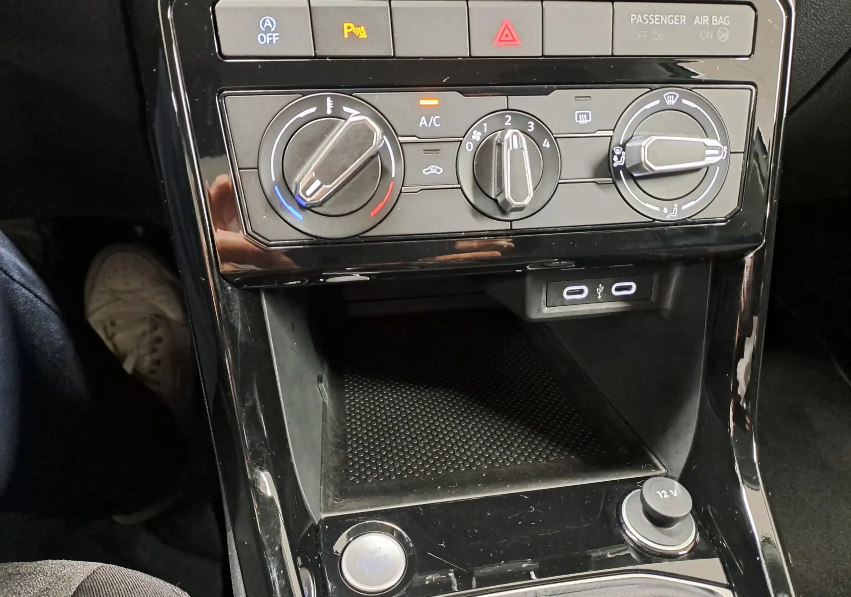 Vue rapprochée de la console centrale du Volkswagen T-Cross 2024 avec commandes manuelles de climatisation et prises USB.