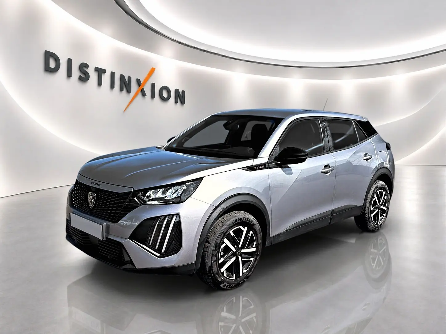 Peugeot 2008 gris en 3/4 avant droit, avec jantes noires et détails noirs sur les rétroviseurs et bas de caisse.