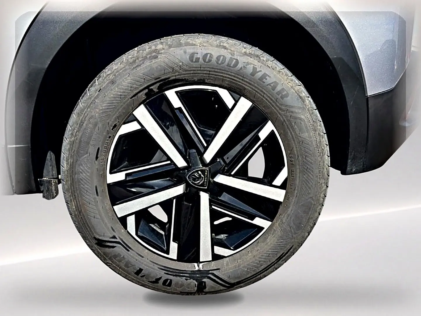 Gros plan sur la roue avant droite du Peugeot 2008 gris, mettant en valeur la jante noire et argentée au design moderne.