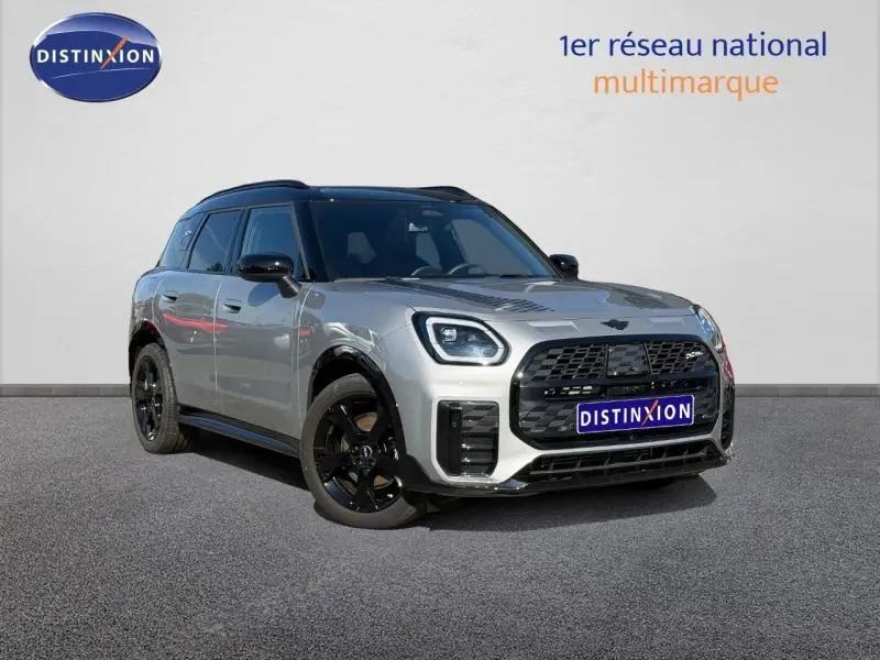 Vue 3/4 avant d'un MINI Countryman C 170ch JCW DKG7 argenté avec jantes noires et toit noir, sur fond neutre.