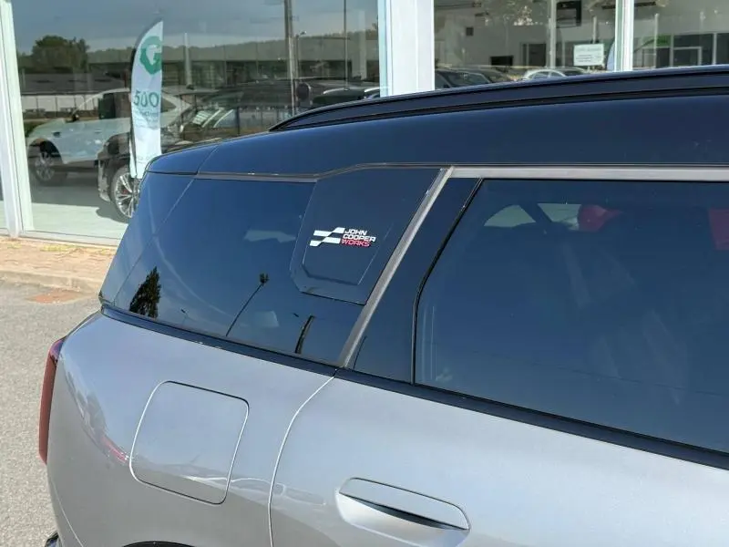 Vue latérale arrière droite d'une MINI Countryman argentée avec toit noir et logo John Cooper Works sur la custode.