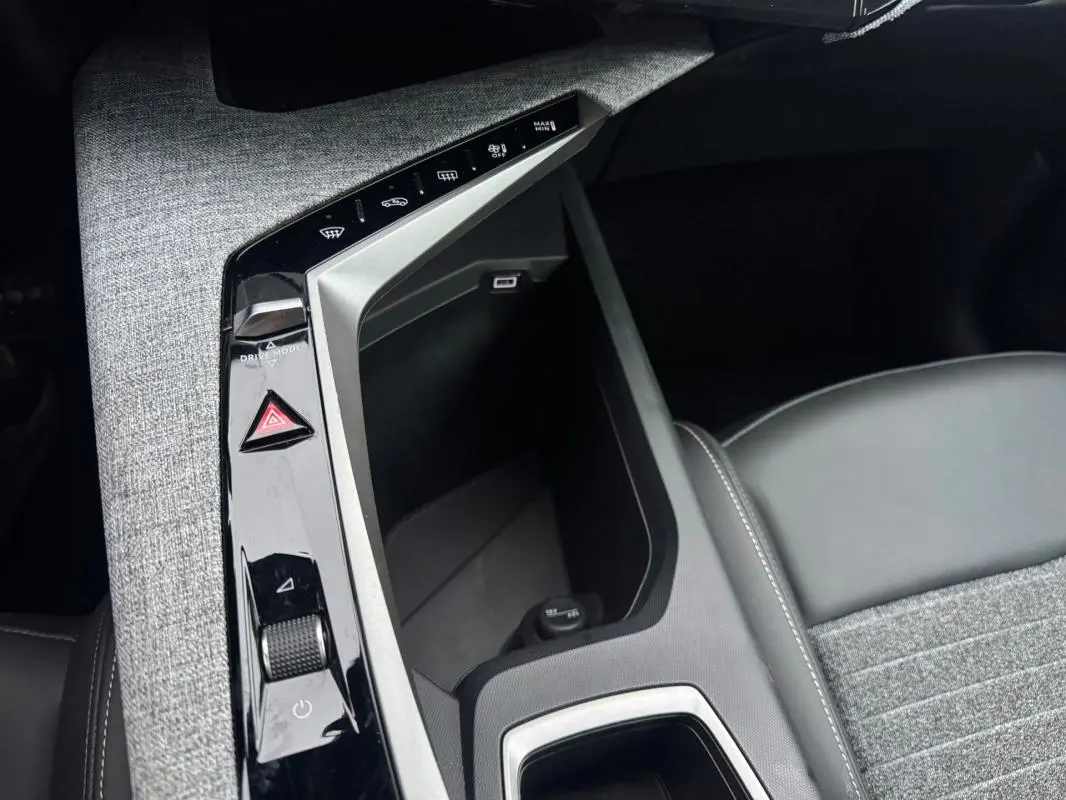 Vue rapprochée de la console centrale du Peugeot 3008 Hybrid 145 Allure 2025 avec commandes tactiles et accoudoir gris.