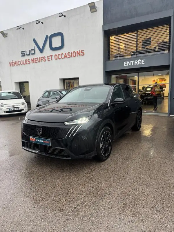 Peugeot 3008 Hybrid noir vue 3/4 avant droit, feux allumés, jantes alliage 19 pouces, devant concession Sud VO.