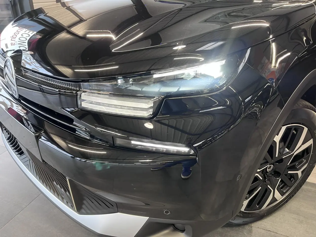 Vue 3/4 avant droit d'une Citroën C4 noire métallisée avec phares LED et jantes alliage 18 pouces.