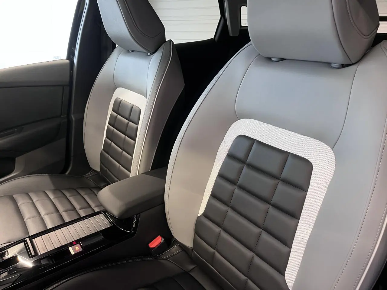 Gros plan sur les sièges avant gris clair et noir avec accoudoir central de la Citroën C4 2025.
