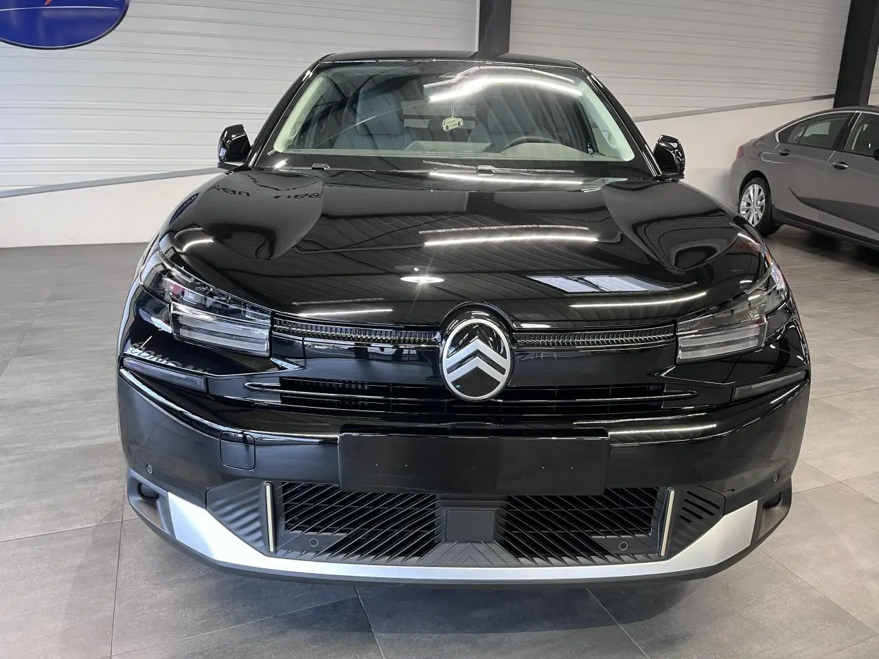 Vue frontale d'une Citroën C4 2025 noire métallisée avec calandre distinctive et détails argentés au pare-chocs.