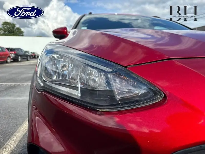 Gros plan sur le phare avant gauche d'une Ford Focus 1.0 EcoBoost 2020 en rouge Premium Candy, avec reflet brillant.