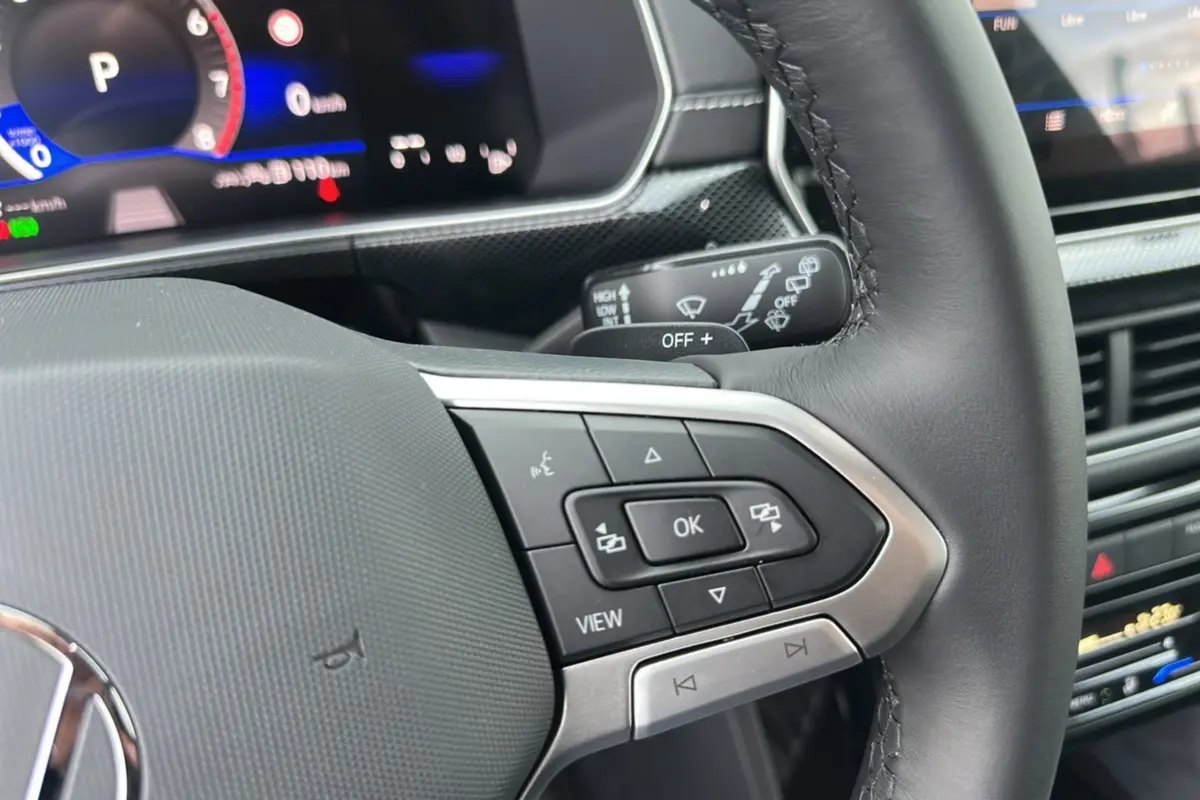 Gros plan sur le volant cuir multifonctions noir du Volkswagen T-Cross 2025 avec tableau de bord digital et commandes intégrées.