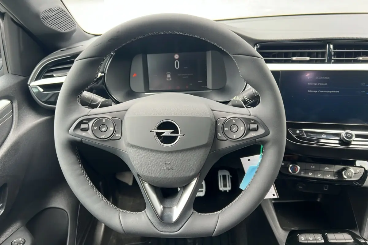 Vue intérieure centrée sur le volant cuir multifonctions Opel Corsa Hybrid 110 e-DCT6 avec tableau de bord numérique.