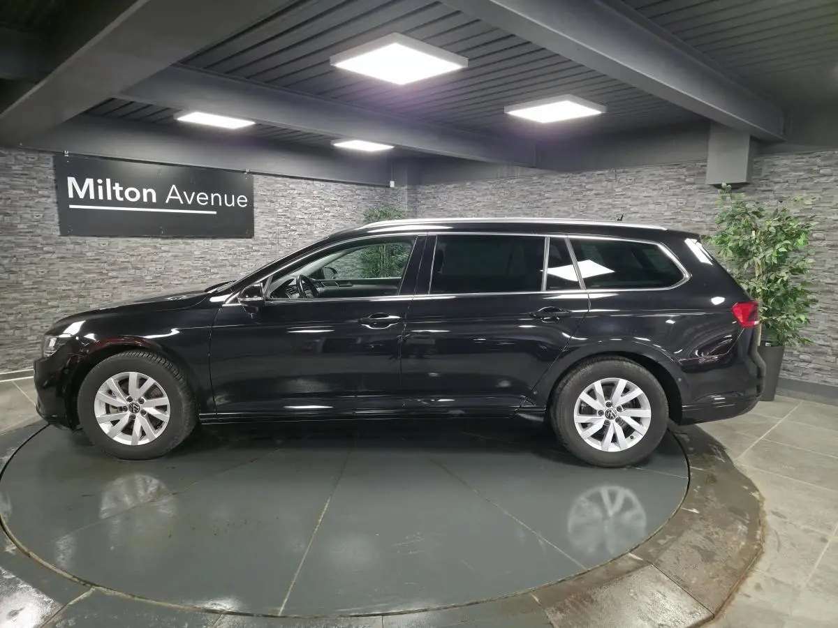 Vue latérale droite d'une Volkswagen Passat SW noire avec vitres arrière surteintées dans un showroom.
