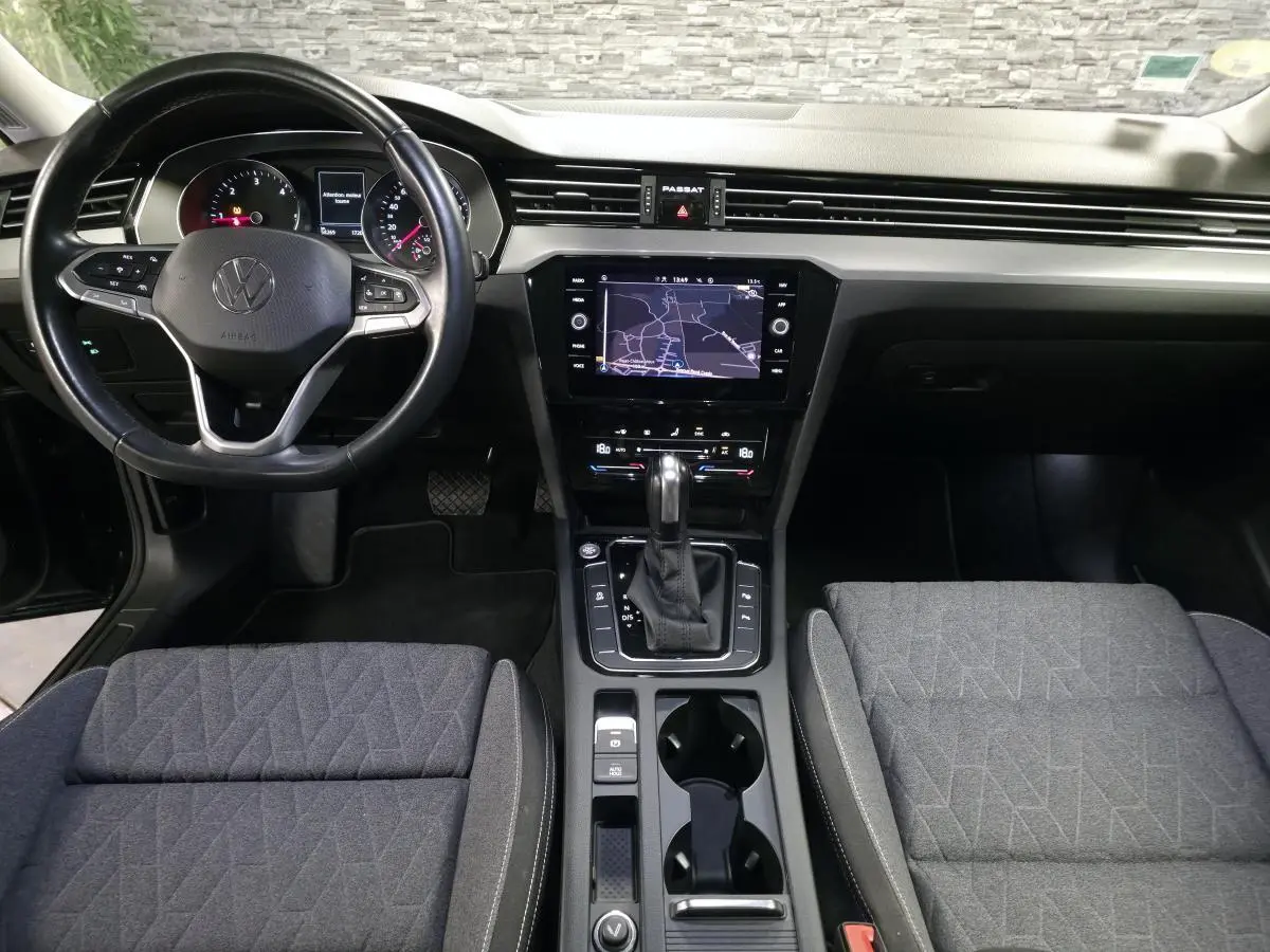 Vue intérieure avant de la Volkswagen Passat SW 2023, tableau de bord noir avec écran tactile et sièges tissu gris.