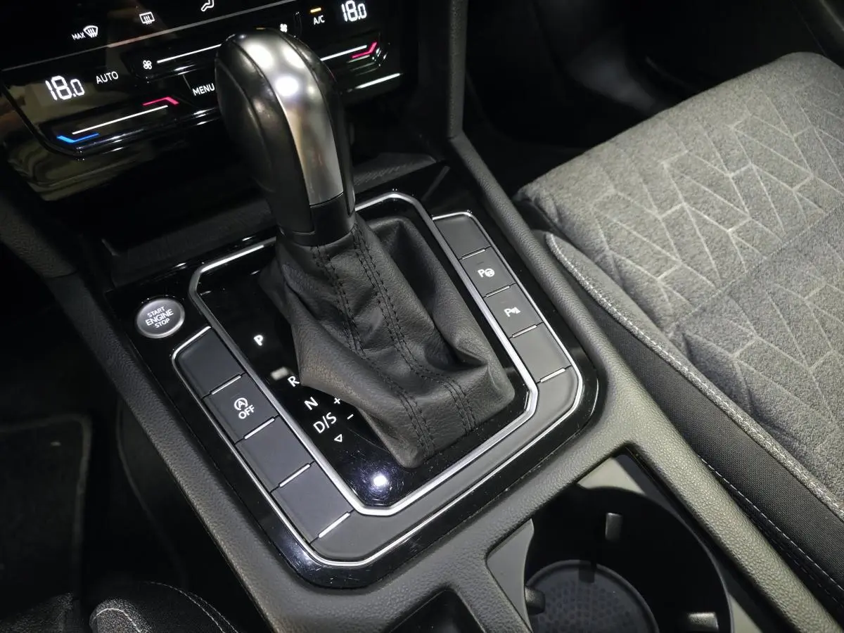 Gros plan sur la console centrale de la Volkswagen Passat SW 2023, levier de boîte auto et siège tissu gris.