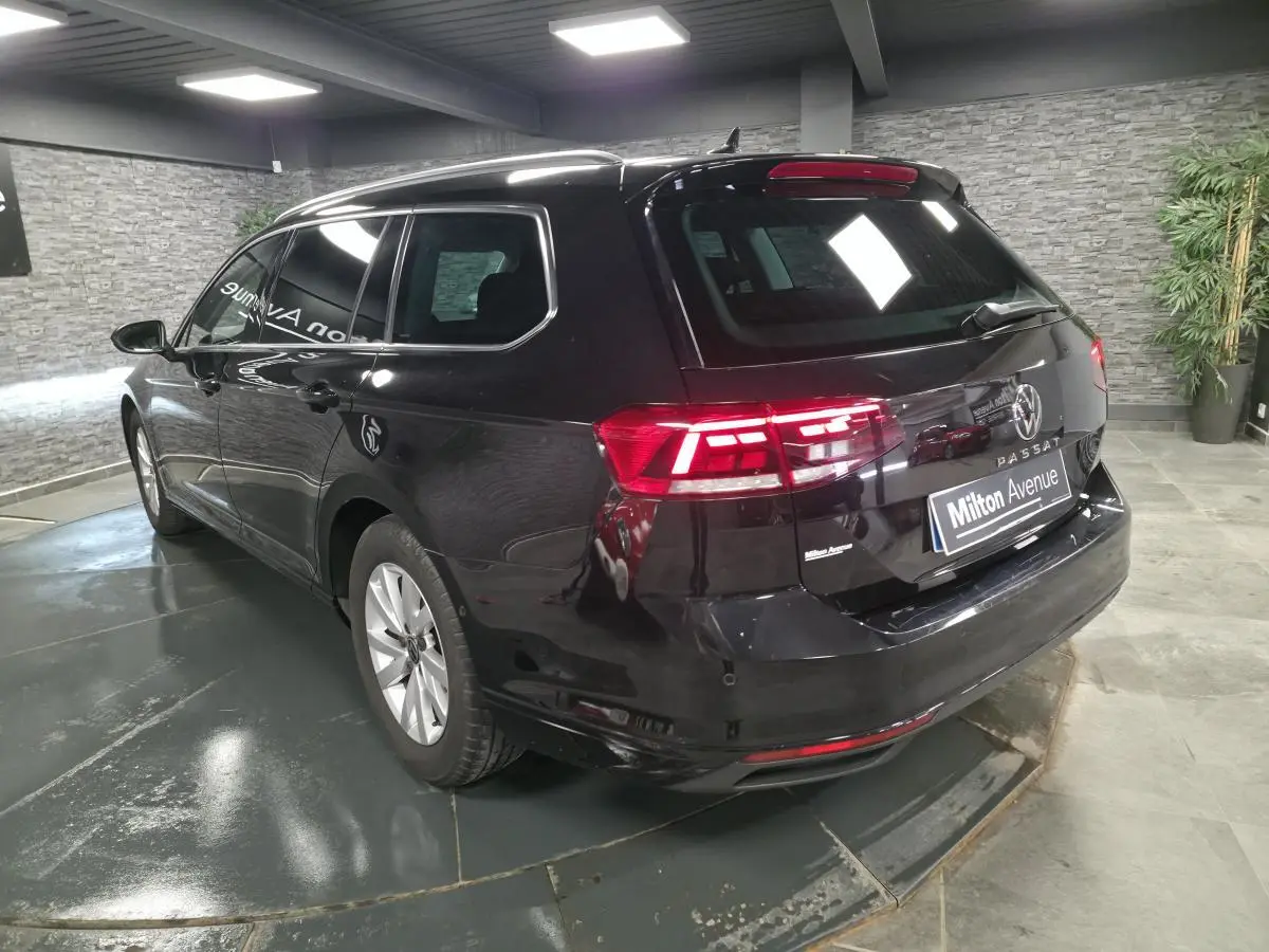Volkswagen Passat SW noire vue 3/4 arrière droit avec vitres arrière surteintées en intérieur showroom.