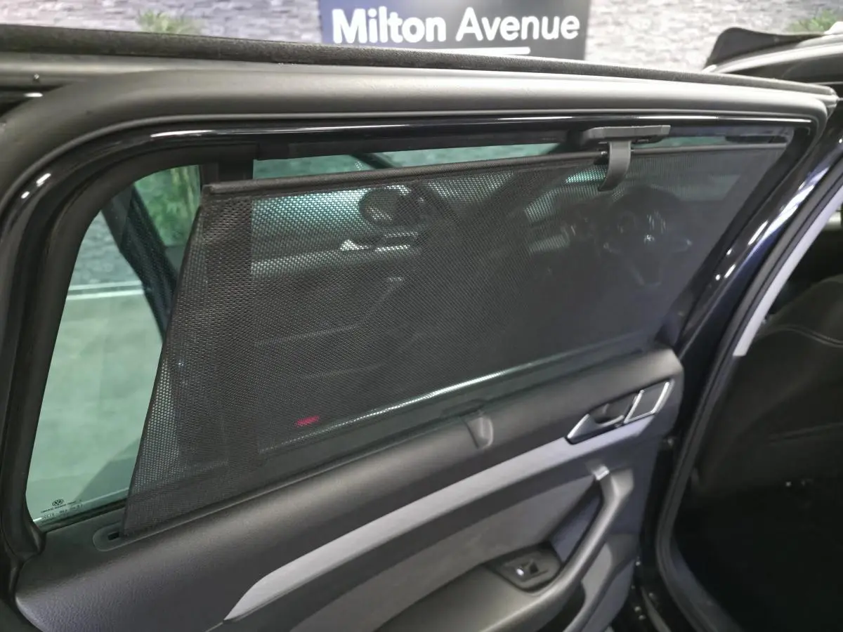 Vue intérieure côté gauche de la porte arrière noire de la Volkswagen Passat SW 2023 avec pare-soleil en filet déployé.