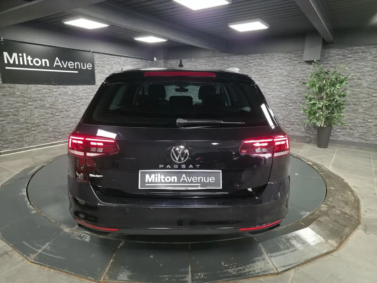 Vue arrière d'une Volkswagen Passat SW noire avec feux LED allumés dans un showroom intérieur.