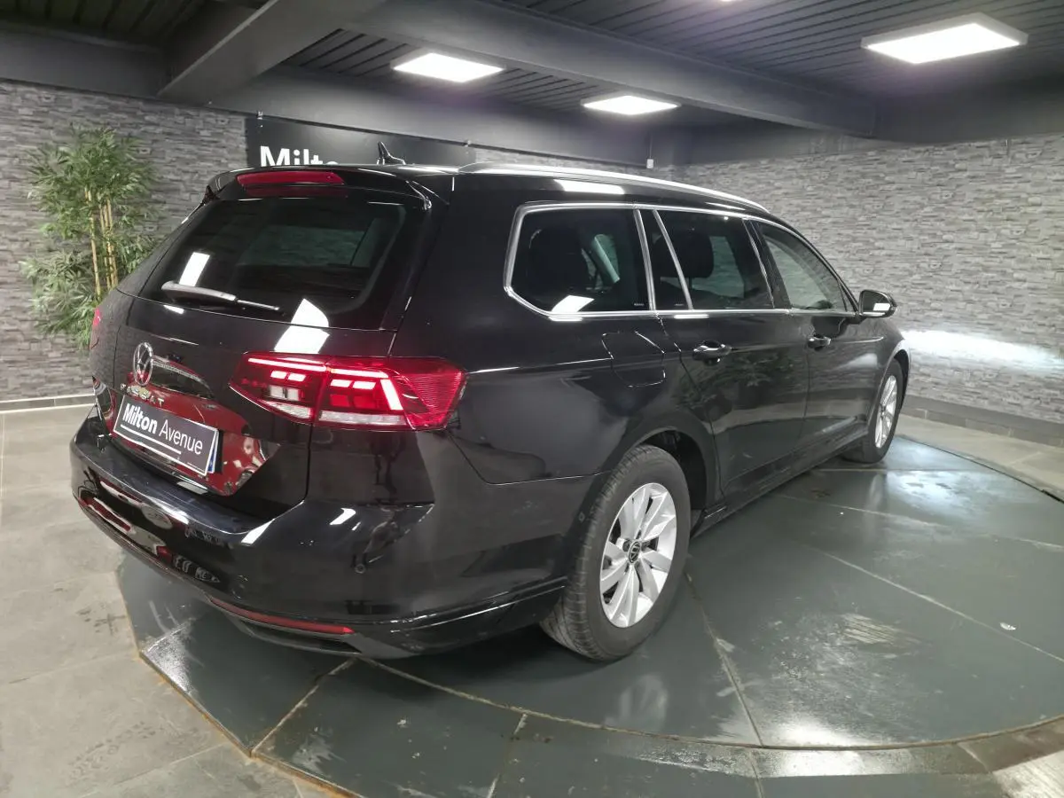 Volkswagen Passat SW noire vue 3/4 arrière droit en intérieur avec vitres arrière surteintées.