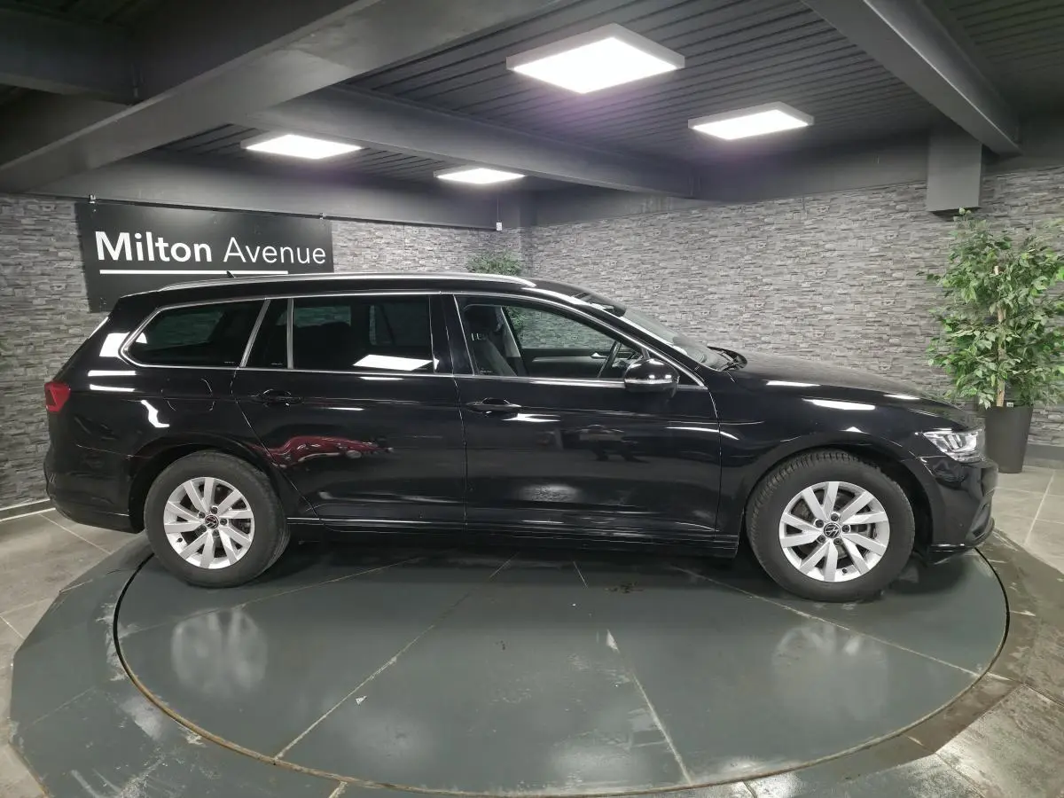 Volkswagen Passat SW noire vue de profil côté gauche en intérieur avec jantes alliage argentées.