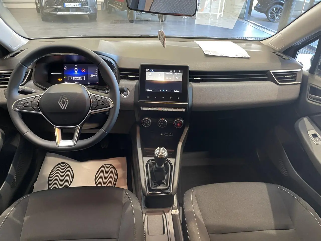 Vue intérieure avant de la Renault Clio 1.5 Blue dCi 2025, tableau de bord gris avec écran tactile et boîte manuelle.