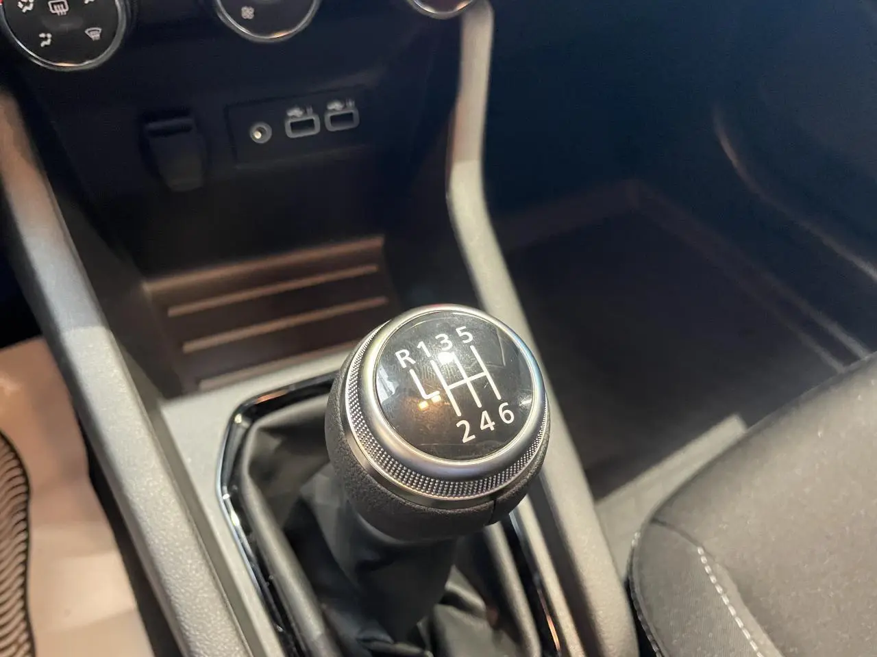 Gros plan sur le levier de vitesses manuel noir de la Renault Clio 1.5 Blue dCi gris Rafale, intérieur sombre.