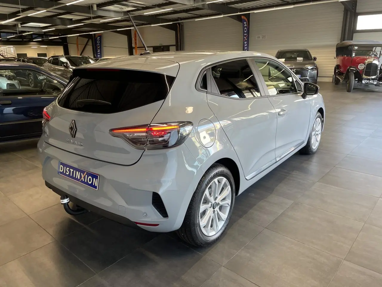 Renault Clio 1.5 Blue dCi gris Rafale vue 3/4 arrière droit en intérieur avec feux arrière LED allumés.