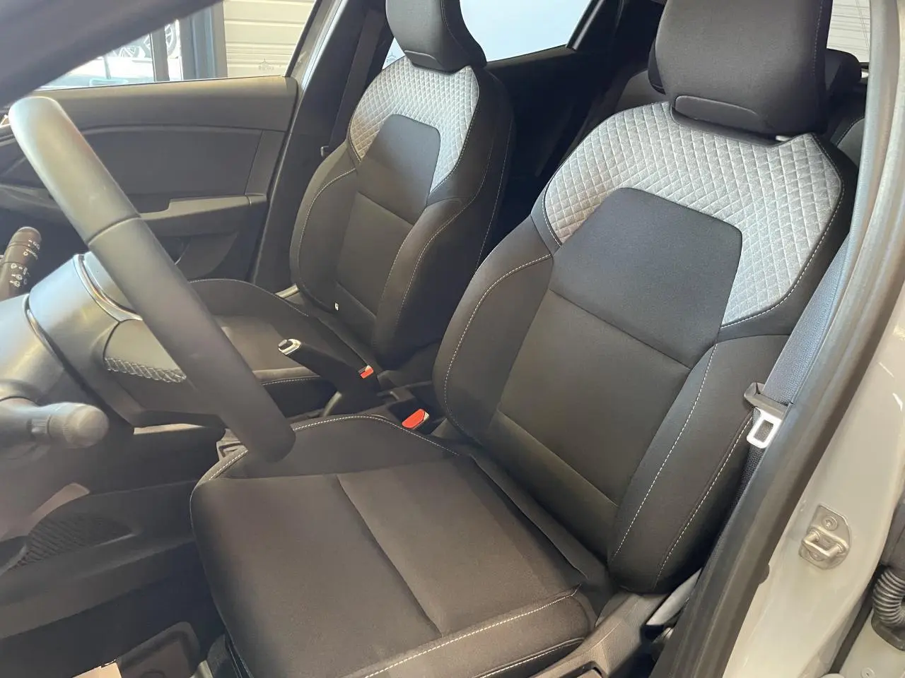 Vue intérieure côté conducteur de la Renault Clio 1.5 Blue dCi 2025 avec sièges tissu gris à motifs 3D twida.