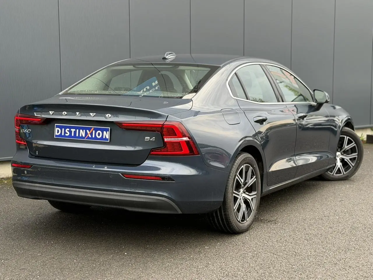 Vue 3/4 arrière droite d'une Volvo S60 B4 gris Denim avec jantes alliage 17 pouces et feux arrière LED.