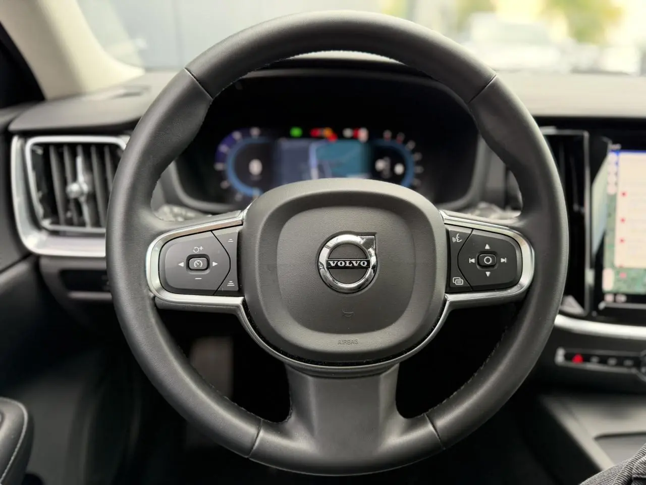 Volant noir de Volvo S60 2024 en vue frontale avec tableau de bord digital et écran tactile visible.