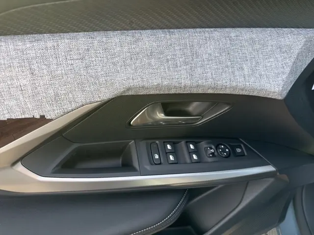 Détail de la porte côté conducteur du Peugeot 3008 bleu 2026, avec commandes électriques des vitres et poignée argentée.